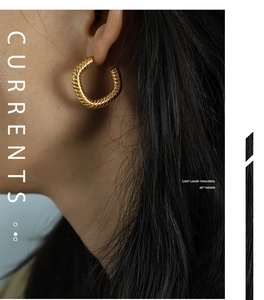 Detail of gold twisted rope textured hoop earrings on model showing metal luster