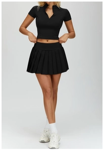 Front view of black pleated tennis skirt and zip-up cropped top for fitness workout