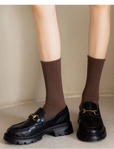 Gros plan de chaussettes en coton marron foncé portées avec des mocassins noirs chics