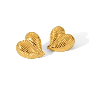 Detailed view of heart-shaped 18K gold earrings with textured vertical ridges on metal