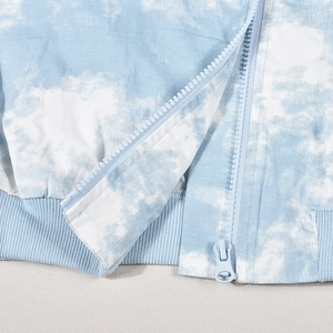 Dettaglio della cerniera in resina e polsini a costine sulla felpa tie-dye blu e bianca
