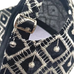 Detail view of heart baseball cap featuring white embroidery and gold metal buckle