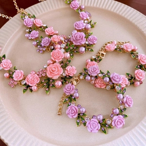 Detail view of floral necklace and bracelet with resin roses and pearls in a ceramic tray