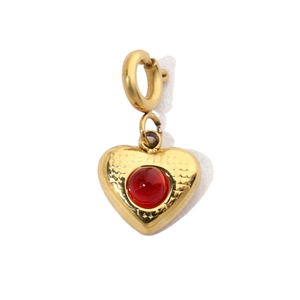 Detail of a gold heart pendant with red stone inlay and hammered metal texture