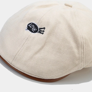Dettaglio ravvicinato di basco in lana beige con ricamo a corona e bordo in cuoio