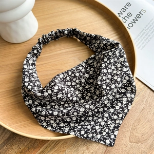 Close-up of black floral headband with white daisy pattern on a wooden tray