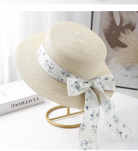 Détail d'un chapeau de paille canotier avec ruban floral sur support doré