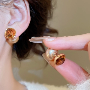 Detailed side view of two-way gold-plated earrings with amber crystal and champagne bead