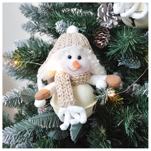 Detail of plush snowman Christmas bell hanging on a tree with festive pine cones