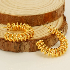 Close-up of golden spring hoop earrings with spiral design on natural wood base