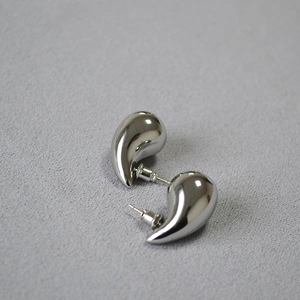 Detailed close-up of chunky silver teardrop earrings with a mirror polished finish
