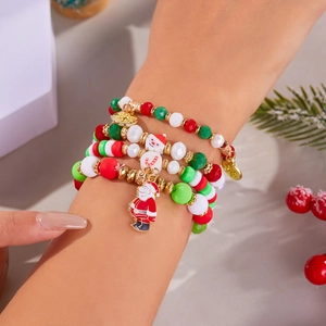 Christmas beaded bracelet set with Santa pendants worn by model against pine background