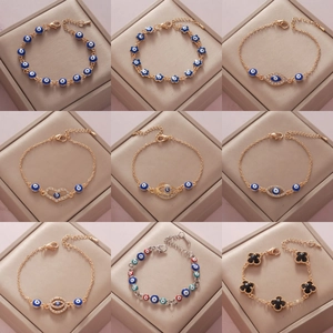 Collection of gold and silver charm bracelets with evil eye and clover patterns