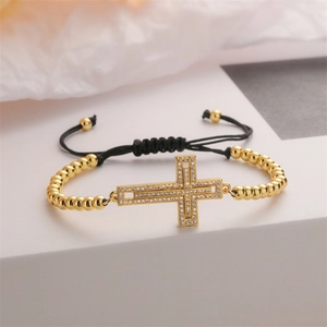 Detail of adjustable gold bead bracelet with cubic zirconia cross and black woven cord