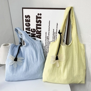 Detail of waffle texture canvas tote bags in blue and yellow with daisy charms