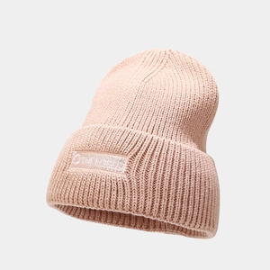 Detailed close-up of pink knit beanie showing the focus embroidery and ribbed texture