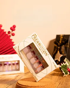 Detail of French burgundy press-on nails with champagne rhinestones on a gift box background