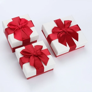 Three red and white square jewelry gift boxes with satin bows on a white background