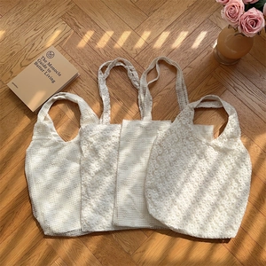 Detail of white mesh lace tote bags with floral texture on a vintage wooden floor