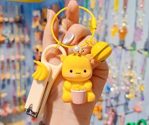 Close-up of yellow cartoon animal keychain with nail clipper and golden bell accessories