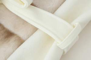 Close-up of cream wool coat detail featuring soft faux fur lining and waist belt loop