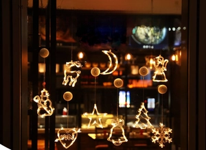Detail of warm yellow LED hanging lights with reindeer and star shapes on a window
