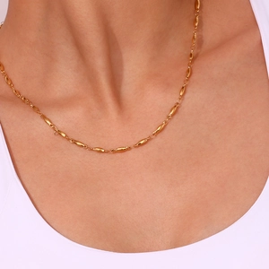 Detailed view of 18K gold plated minimalist olive link chain worn on the collarbone