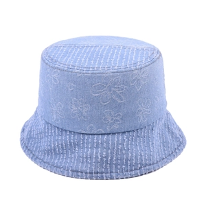Detail of light blue denim bucket hat with white contrast stitching and floral patterns