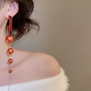 Detail of long vintage drop earrings with caramel hooks and four orange-red pearls