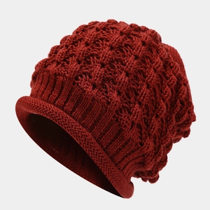 Close-up of deep red winter knit beanie showing chunky texture and rolled edge detail