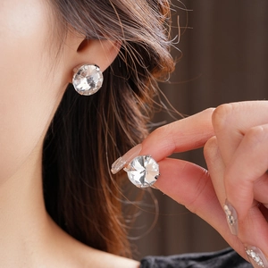 Close-up of sparkling four-prong round zircon stud earrings worn by a female model