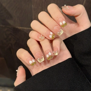 Faux ongles œil de chat rose avec motifs floraux blancs et pointes French dorées