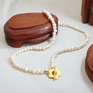 Baroque freshwater pearl necklace with gold flower OT clasp on natural textured surface