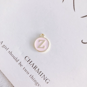 Detailed view of round pink enamel pendant with gold letter Z for DIY jewelry making