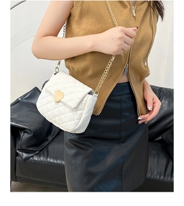 Detail of white quilted crossbody bag with golden heart clasp and metal chain strap