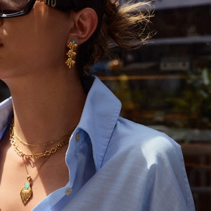 Close-up of vintage gold necklace and feather earrings set with turquoise stones