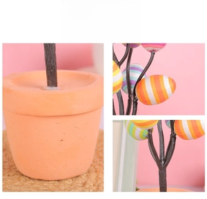Détail d'un bonsaï d'oeufs de Pâques avec oeufs rayés et pot orange sur rose