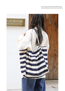 Detailed view of striped canvas tote bag showing size and drape on model shoulder