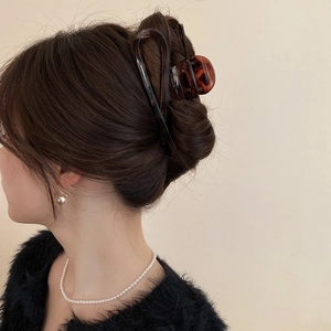 Detail of amber leopard hair claw clip worn by a model with elegant pearl jewelry