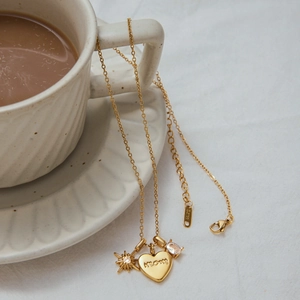 Detail of gold stainless steel necklace with MOM heart, starburst and gem pendants