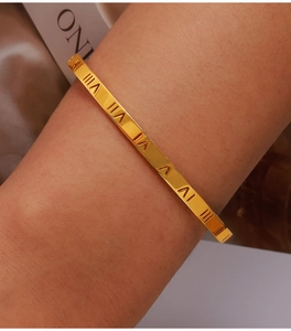 Close-up of gold-plated titanium bracelet featuring Roman numerals and inset diamonds