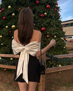 Detailed back view of a black bodycon dress featuring a large white satin bow detail