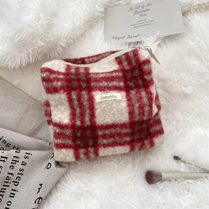 Detailopname van rood-witte ruitjes make-uptas met merklabel en ritssluiting bovenaan