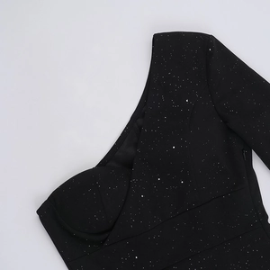Detalle de vestido negro de un hombro con purpurina plateada y textura fruncida