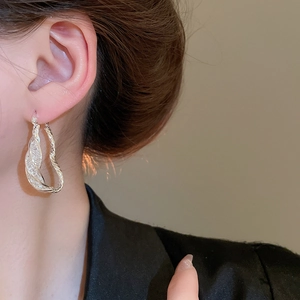 Detail of silver twisted hoop earrings with sparkling zircons on a female model