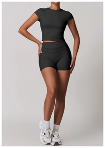 Dettaglio del set yoga nero elasticizzato con crop top e pantaloncini sportivi a vita alta