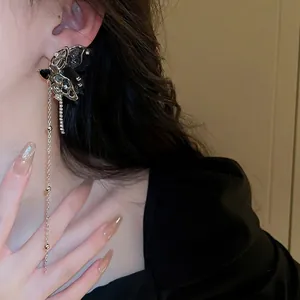 Elegant gold and black butterfly tassel earrings with crystals worn by model in close-up
