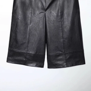 High-waist black faux leather wide-leg bermuda shorts with textured finish on white background