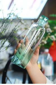 Close-up of clear glass water bottle with green gradient and time markers for hydration
