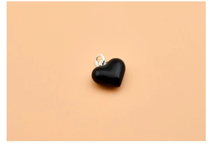 Detailed view of a black enamel heart pendant with a polished silver bail attachment